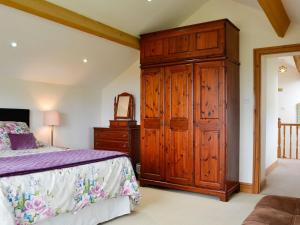a bedroom with a large wooden cabinet and a bed at Farm Cottage in Cleator