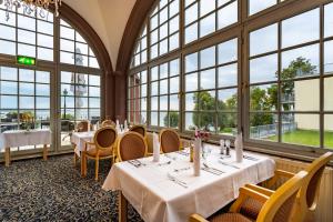 ein Restaurant mit Tischen und Stühlen und großen Fenstern in der Unterkunft Seehotel Schloss Klink in Klink