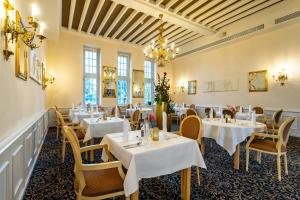 een eetkamer met tafels en stoelen en een kroonluchter bij Seehotel Schloss Klink in Klink