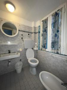 bagno con servizi igienici, lavandino e specchio di Hotel villa del bagnino a Rimini