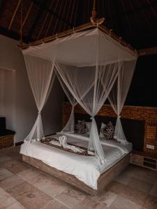 a bedroom with a canopy bed with white sheets and pillows at Tirta Sari in Tampaksiring