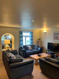 a living room with couches and a flat screen tv at Chy Lowen - Atlantic Reach in Newquay