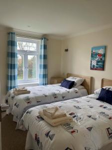 a bedroom with two beds and a window at Chy Lowen - Atlantic Reach in Newquay