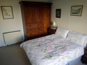 a bedroom with a bed with a wooden dresser and a dresser at Tranquil getaway on edge of the Brecon Beacons in Llandovery