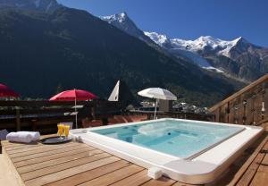 a hot tub on a deck with mountains in the background at Park Hotel Suisse & Spa in Chamonix