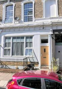 a red car parked in front of a house at Tulip 5 Top Floor at Hammersmith in London