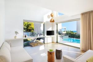 a living room with white furniture and a large window at Cavo Delea Villas & Suites in Possidi