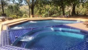 uma grande piscina com piso em azulejo azul e azulejos azuis em Refúgio Serra Negra em Serra Negra