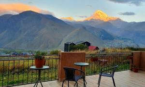 a balcony with two chairs and a table with a view of mountains at Apartment Nikolo in Stepantsminda