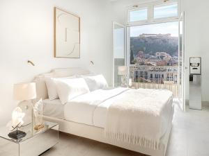a white bedroom with a bed and a large window at The Dolli at Acropolis in Athens