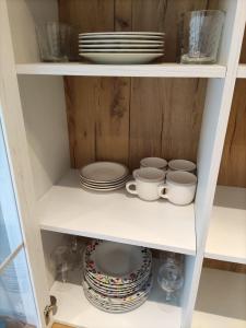 a white shelf with plates and cups and dishes at Apartamentos Baldenora in Llanes