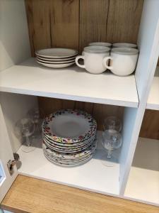 a white shelf with plates and cups and dishes at Apartamentos Baldenora in Llanes