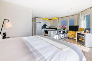 a white bedroom with a white bed and a kitchen at Pier View Suites - Studio A in Cayucos