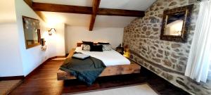 - une chambre avec un lit et un mur en pierre dans l'établissement Maison familiale chaleureuse idéalement située, à Silhac
