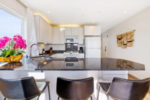 uma cozinha com armários brancos e bancadas pretas em Pier View Suites - Studio B em Cayucos