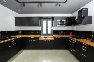 eine Küche mit schwarzen Schränken und Arbeitsflächen aus Holz in der Unterkunft Villa Athos in Gouvia