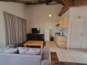 a living room with a couch and a table and a kitchen at Qabuleka BnB in Nongoma