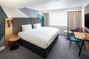 イーストリーにあるHoliday Inn Southampton Eastleigh, an IHG Hotelのベッドとデスクが備わるホテルルームです。