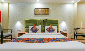 a bedroom with a large bed and a chair at FabHotel Aerosky Grand in New Delhi
