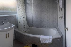 a bathroom with a bath tub and a sink at The glorious 3 bedroom apartment with parking in Nottingham