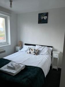 a bedroom with a bed with white sheets and a window at The glorious 3 bedroom apartment with parking in Nottingham