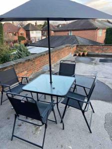 una mesa y sillas con una sombrilla en el patio en The glorious 3 bedroom apartment with parking en Nottingham