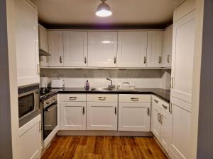 a kitchen with white cabinets and a sink at Stylish Luxury Serviced Apartment next to City Centre with Free Parking - Contractors & Relocators in Coventry