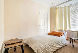 1 dormitorio con cama, mesa y ventana en 2 bed terraced house with loft in Stratford London en Londres