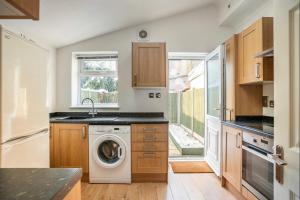 a kitchen with a washing machine and a window at 2 bed terraced house with loft in Stratford London in London