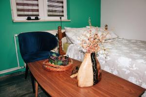 a wooden table with a vase with flowers and a chair at Villa Mihajlovo in Kavadarci