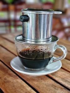 a cup of coffee on a saucer with a pot on it at Phuc Sinh Homestay in Ben Tre