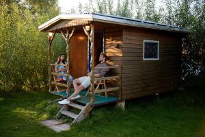 Dos mujeres sentadas en el porche de una casa pequeña en Wakenitz-Camp en Groß Sarau