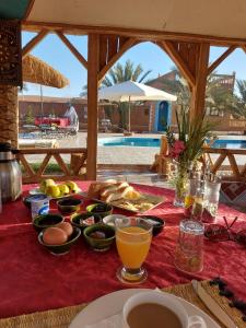 a table with food and drinks on a red table cloth at Oasis Tilogui in Zagora