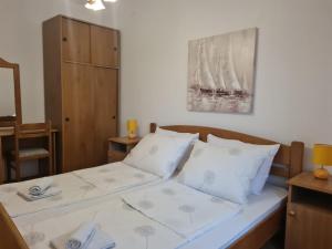 Schlafzimmer mit einem Bett mit weißer Bettwäsche und Kissen in der Unterkunft Apartments Kesic in Barbat na Rabu