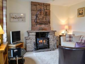 a living room with a fireplace and a tv at Rose Cottage in Cleator