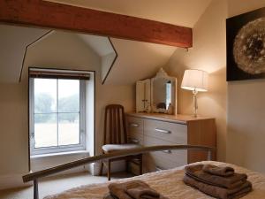 a bedroom with a bed and a dresser and a window at Rose Cottage in Cleator