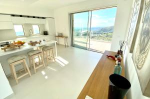 a white kitchen with a table and a large window at Villa Olimpo in Avola