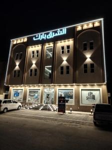 a large building with a sign on it at night at Al Shark Park Serviced Apartment in Al Mikhlaf
