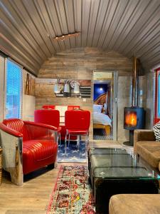 a living room with red furniture and a bed at Gleis 2, Waggon mit Ofen, Whirlpool und Sauna in Dahlem