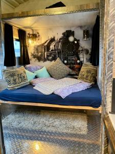 a bed in a room with a train on the wall at Gleis 2, Waggon mit Ofen, optional mit Whirlpool und Sauna in Dahlem