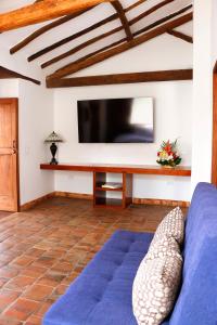 a living room with a blue couch and a flat screen tv at Santa Sofia Casa Boutique in Barichara