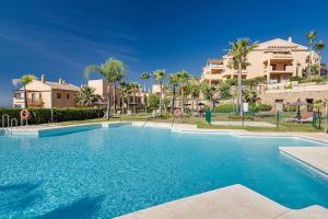 a swimming pool in a resort with palm trees at Superbe appartement avec vue mer in Estepona