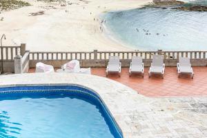 een zwembad met stoelen en een strand bij CASA PLAYA DE LIMENS in Cangas de Morrazo