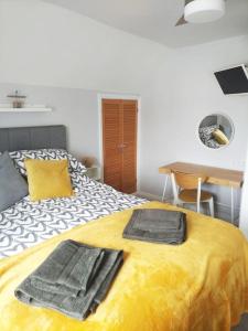 a bedroom with a yellow bed with towels on it at A Pebbles Throw - 300m from the beach. in Westward Ho