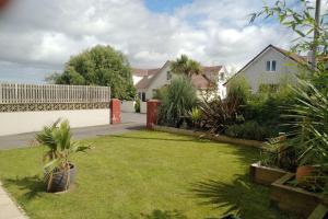 a backyard with a lawn with plants and a fence at A Pebbles Throw - 300m from the beach. in Westward Ho