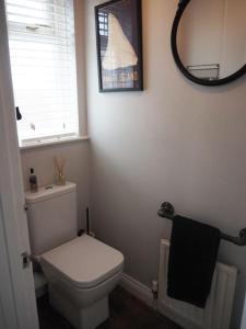 a bathroom with a white toilet and a mirror at A Pebbles Throw - 300m from the beach. in Westward Ho
