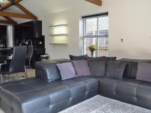 a leather couch in a living room with a kitchen at The Old Stables in South Cave