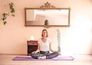a woman sitting on a yoga mat in a room at KACLLA, The Healing Dog Hostel in Lima