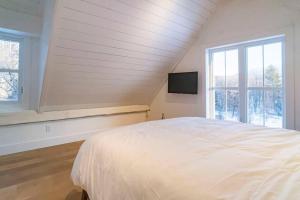 Maison ancestrale complètement rénovée 4 chambres في بورمونت: غرفة نوم بيضاء مع سرير وتلفزيون