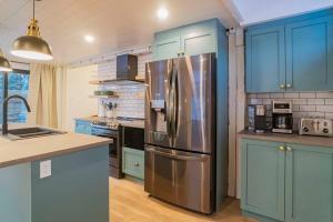 cocina con armarios azules y nevera de acero inoxidable en Maison ancestrale complètement rénovée 4 chambres, en Bromont